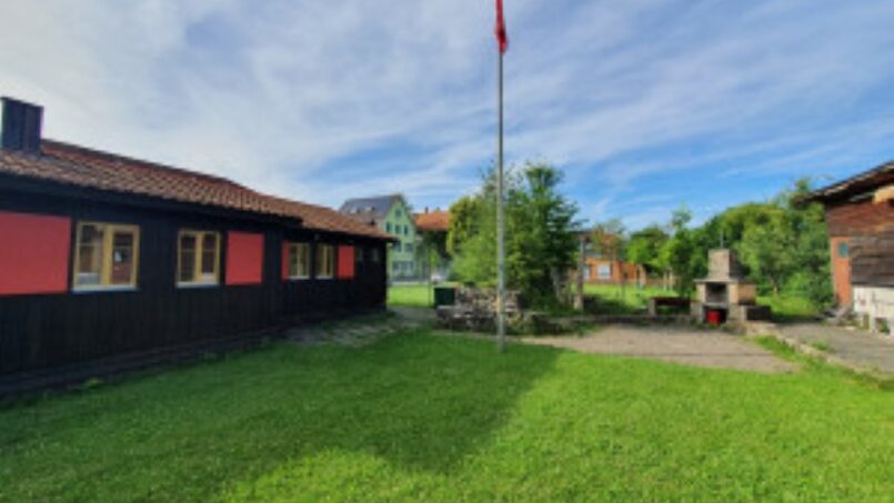 Gruppenhaus-Kadettenhütte-Winterthur-Holzhaus-mit-Flagge-im-Garten