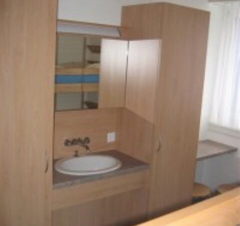 Kleines Zimmer mit Waschbecken und Spiegel im Gruppenhaus Lagerunterkunft Schulhaus in Sörenberg