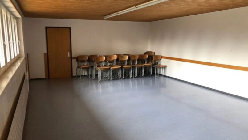 Leeres Zimmer mit Stühlen und Holzdecke im Gruppenhaus Le Refuge in Mont Tramelan