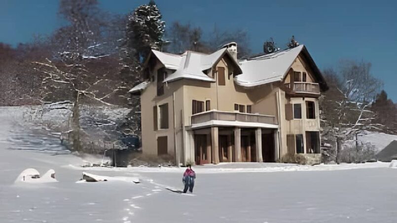 Person steht vor Gruppenhaus Monteret I Schloss in Saint-Cergue im Schnee.