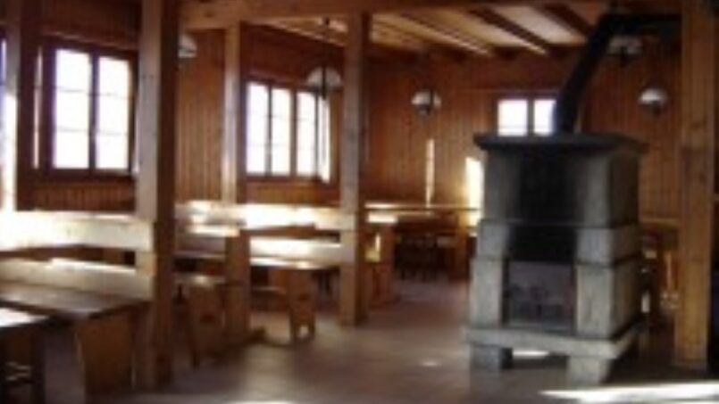 Gruppenhaus Saflischhütte Rosswald ob Brig Esszimmer mit Holztischen und Stühlen und Kamin
