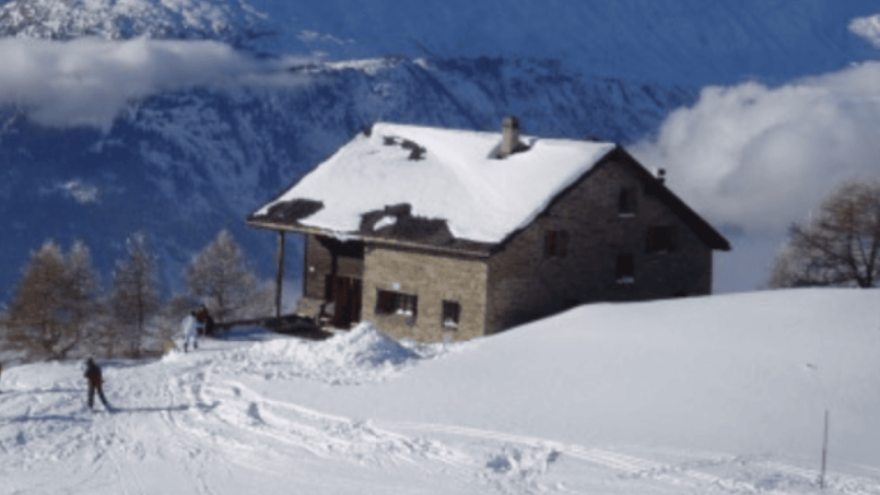 Skifahrer auf verschneiter Piste bei Gruppenhaus Saflischhütte in Rosswald ob Brig