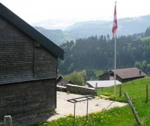 Gruppenhaus Ski- und Clubhaus Pfungen in Ebnat-Kappel, kleines Holzhaus am Hang mit kanadischer Flagge