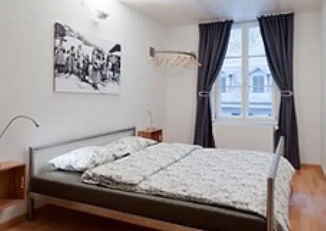 Gruppenhaus Teamhaus Boltigen Schlafzimmer mit Holzboden und Bett