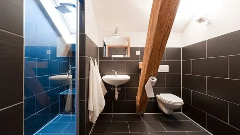 Gruppenhaus Teamhaus Boltigen Badezimmer mit schwarz gefliestem Boden und Holzdecke