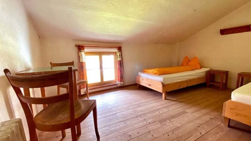 Gruppenunterkunft Ferienhaus Bos-cha in Guarda, Zimmer mit zwei Betten und Holzboden.
