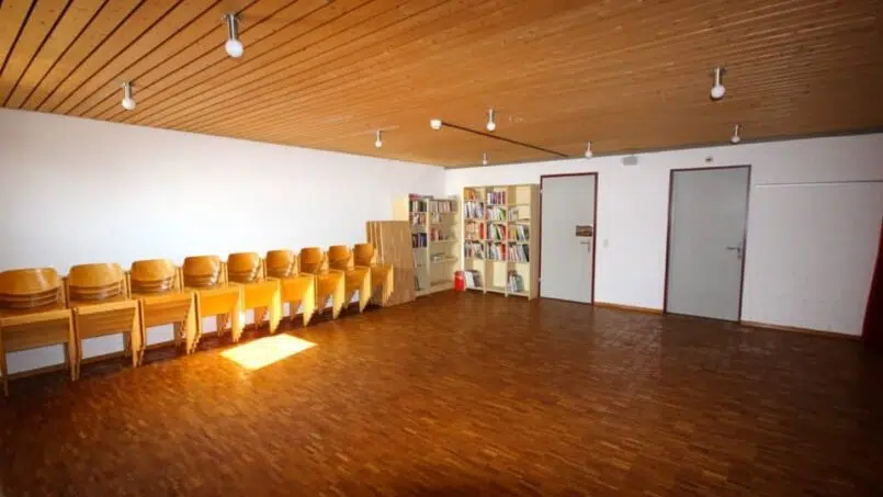 Leeres Zimmer mit Holzboden und Stühlen im Jugendhaus der Heilsarmee Stäfa - Gruppenunterkunft Schweiz