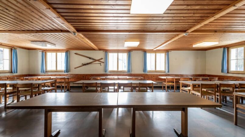 Leerer Klassenzimmer in Gruppenunterkunft Casa Clau in Rueun mit Holztischen und Stühlen