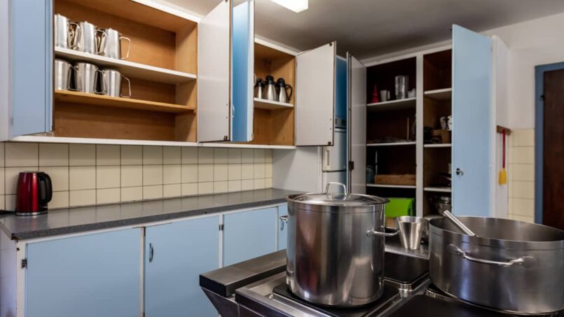Küche mit blauen Schränken und Töpfen in der Gruppenunterkunft Casa Clau in Rueun