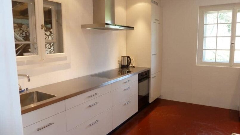 Gruppenhaus Sunnehüsli Vitznau moderne Küche mit weissen Schränken und rotem Boden