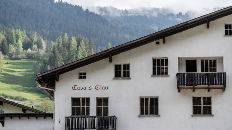 Gruppenunterkunft Casa Clau Rueun - Weißes Gebäude mit Balkonen und Berg im Hintergrund