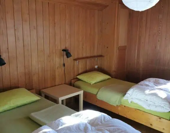 Zwei Betten in einem Raum mit Holzwänden im Gruppenhaus Sunnehüsli in Vitznau
