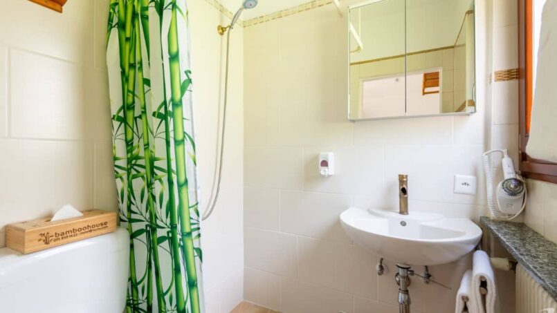 Gruppenhaus-Bamboohouse-Motel-Riazzino-Badezimmer-mit-grünem-Duschvorhang-und-Waschbecken