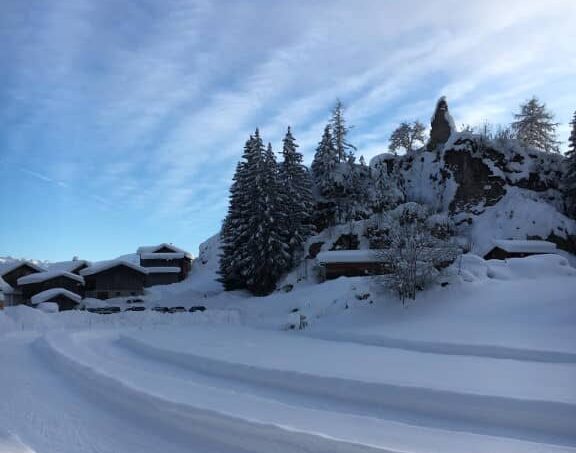 Gruppenunterkunft-Casa-Sentupada-Siat-Skigebiet-mit-verschneiter-Piste-und-Bäumen-im-Hintergrund