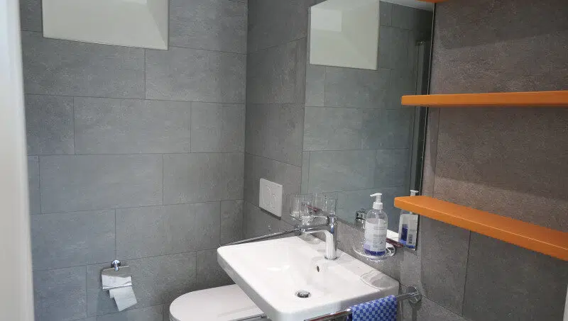 Gruppenhaus La Pineta Badezimmer mit Toilette, Waschbecken und Regalen in Locarno