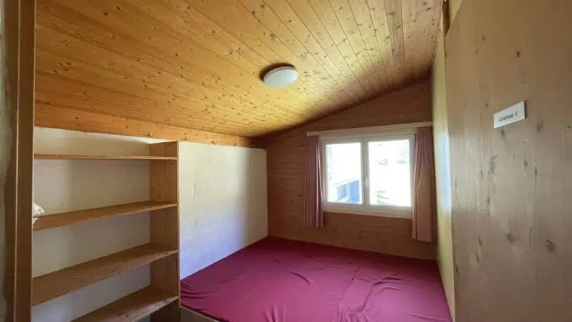 Kleines Zimmer mit Bett und Regal im Clubhaus Alt St. Johann - Gruppenunterkunft