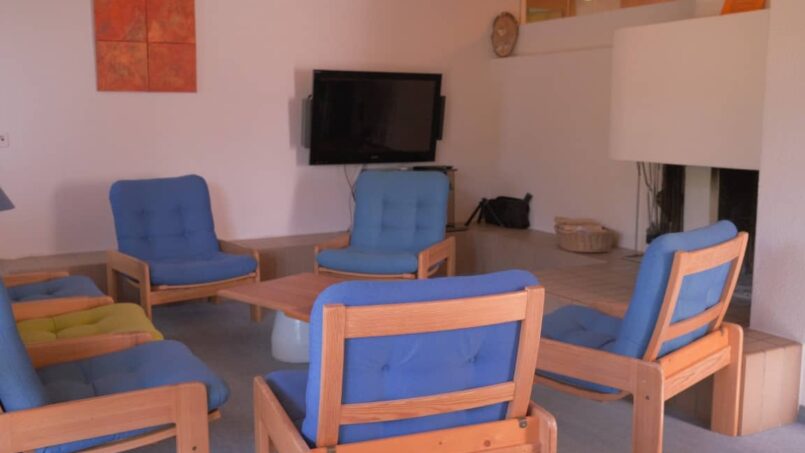 Gruppenunterkunft-CVJM-Zentrum-Hasliberg-Gästehaus-Wohnzimmer-mit-blauen-Stühlen-und-TV
