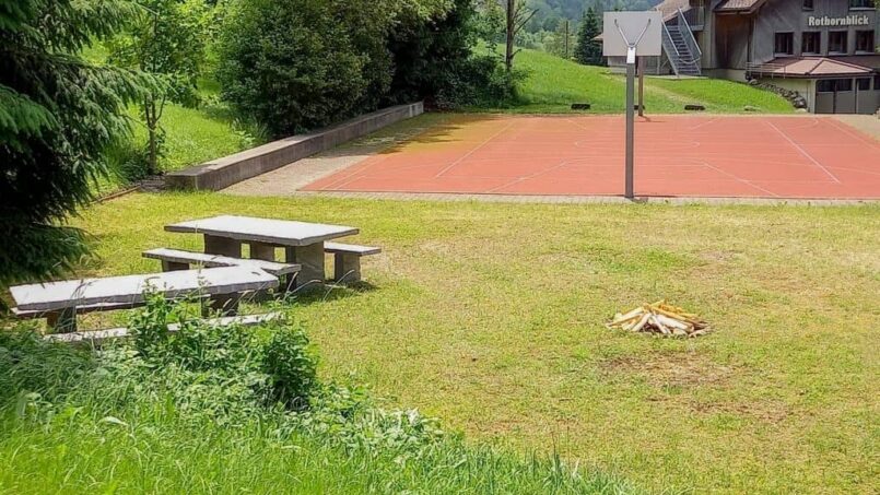 Gruppenunterkunft-CVJM-Ferienheim-Rothornblick-Flühli-Garten-mit-Bänken-und-Basketballplatz