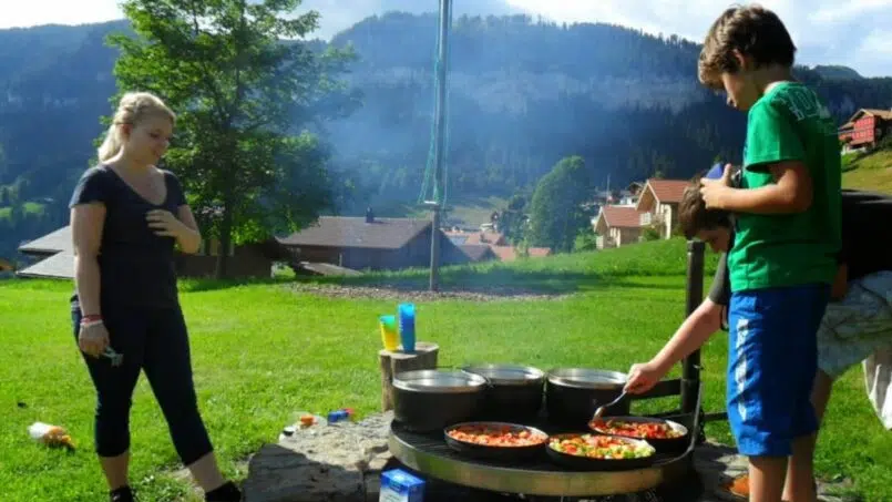 Gruppenunterkunft Jugendhaus Ramsern Beatenberg, Leute bereiten Essen am Lagerfeuer in den Bergen vor.