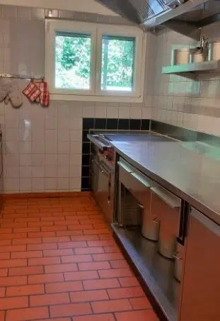 Gruppenhaus-Pfadiheim-Rothburg-Aarburg-moderne-Küche-mit-rotem-Fliesenboden-und-Edelstahlgeräten