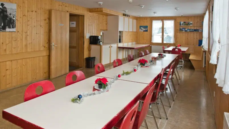 Gruppenhaus-Sonnenrain-Adelboden-weisser-Tisch-rote-Stühle