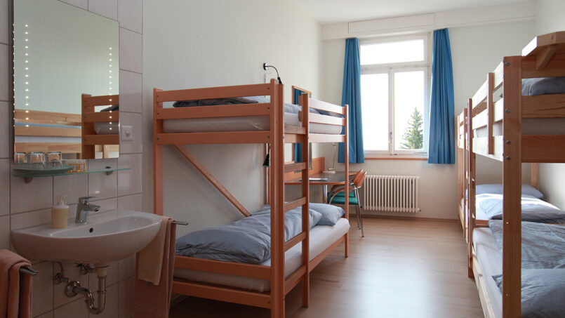 Kleines Zimmer mit Etagenbetten und Waschbecken im Gruppenhaus Weißes Haus in Beatenberg.