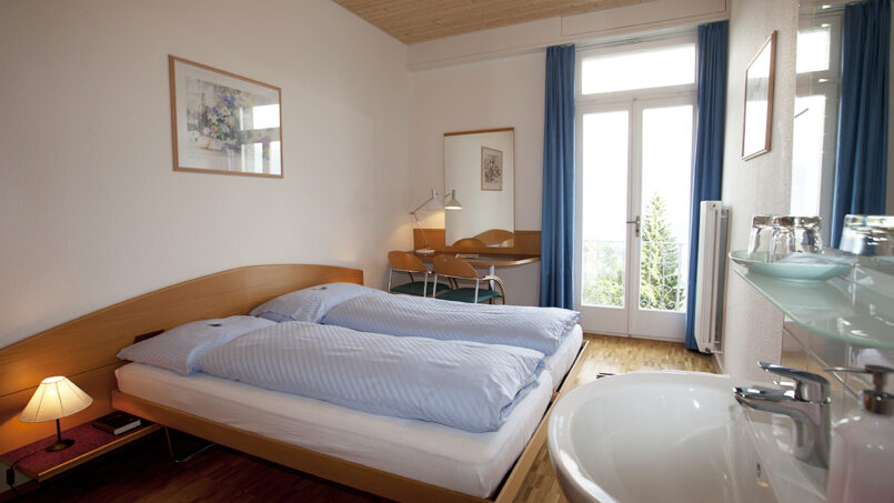 Schlafzimmer mit Bett und Waschbecken im Gruppenhaus Weißes Haus in Beatenberg