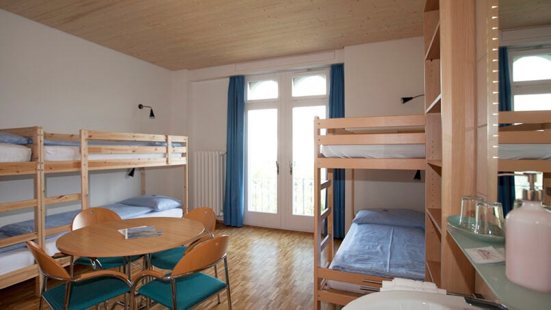 Kleiner Raum mit Etagenbetten und Tisch im Gruppenhaus Weißes Haus, Beatenberg
