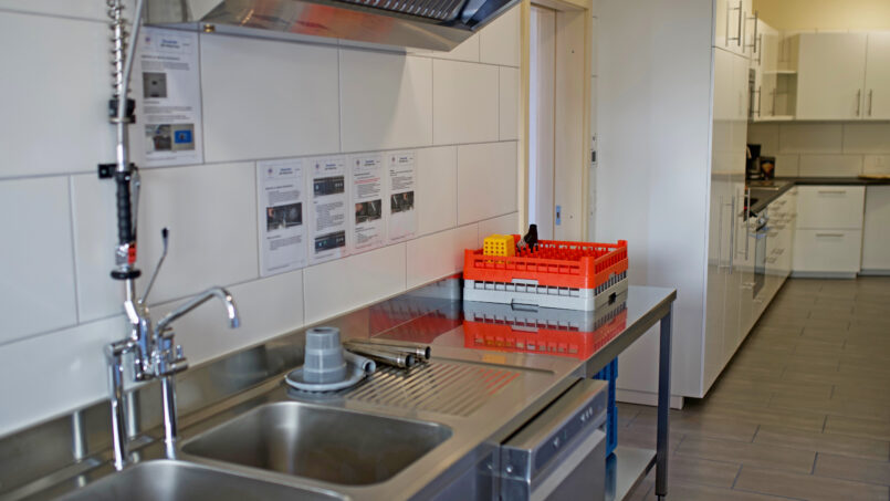 Küche mit Spüle und Dunstabzugshaube im Gruppenhaus Weisses Haus in Beatenberg