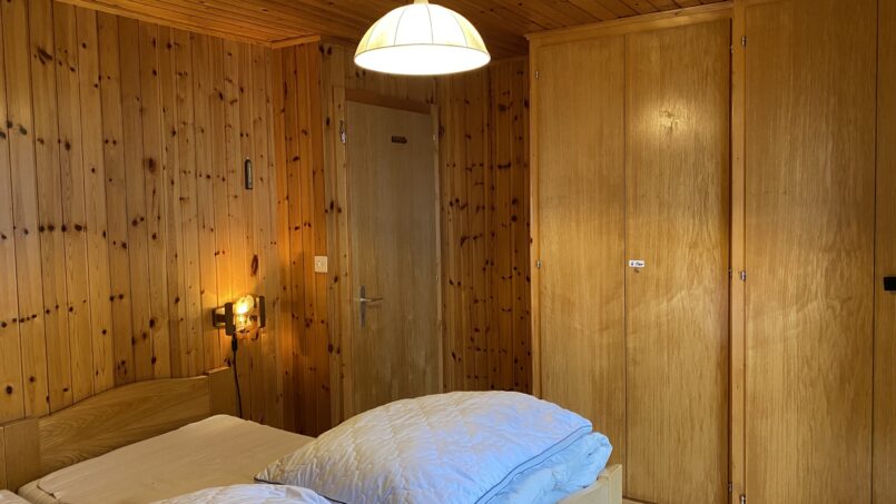 Gruppenhaus Chalet La Marmotte Schlafzimmer mit Holzwänden und Bett in Les Crosets