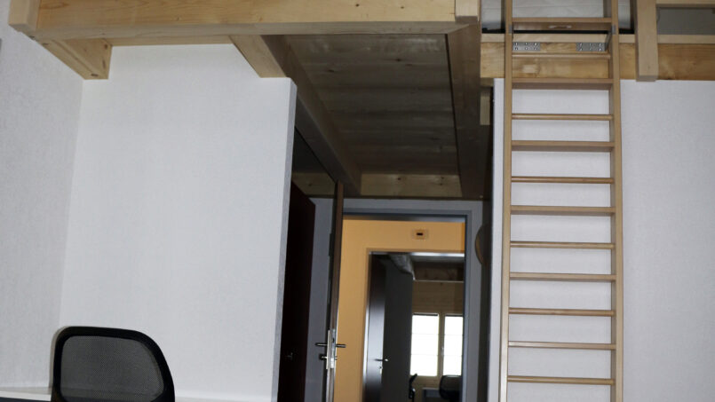 Kleines Zimmer mit Schreibtisch und Leiter im Gruppenhaus Sportlodge Gstaad