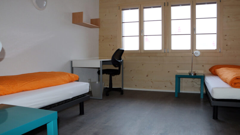 Schlafzimmer im Gruppenhaus Sportlodge Gstaad mit Schreibtisch und Bett