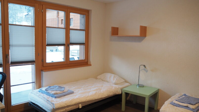 Zweibettzimmer im Gruppenhaus Sportlodge Gstaad mit Schreibtisch