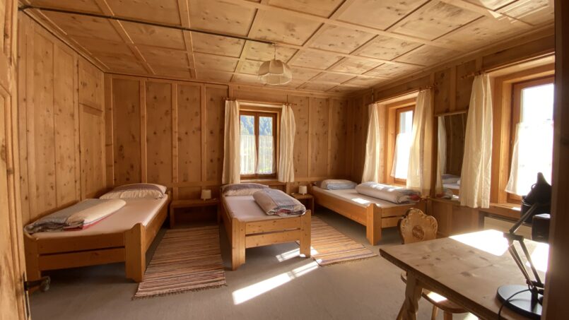 Gruppenhaus Steinbock Val Müstair Holzzimmer mit zwei Betten und Schreibtisch