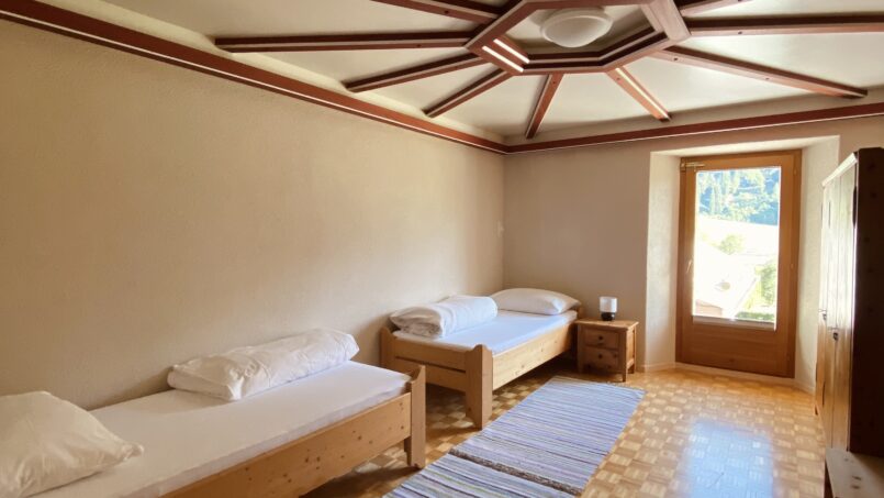 Zweibettzimmer im Gruppenhaus Steinbock in Val Müstair mit gestreiftem Teppich